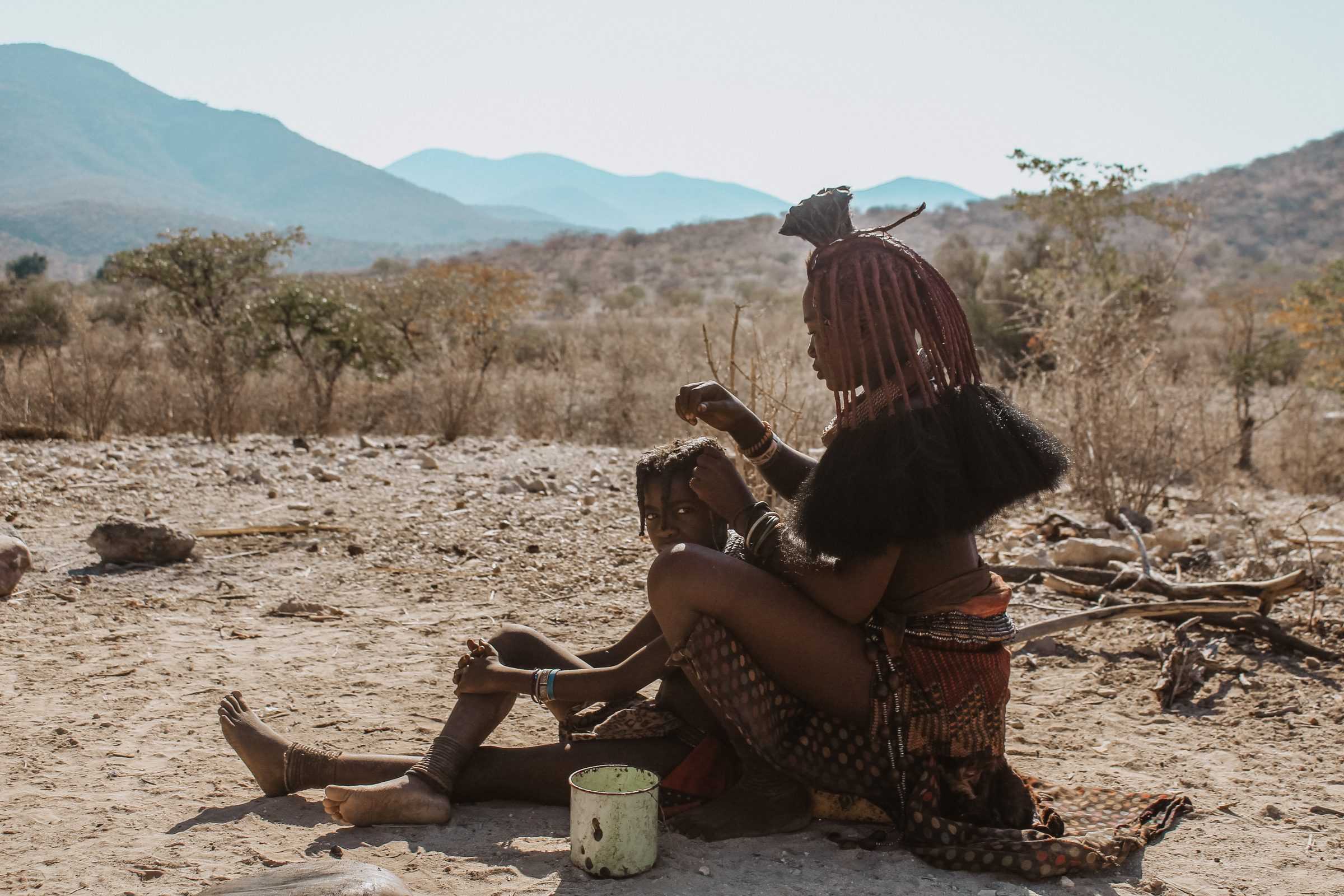Himba stam: De vlechten van een jong meisje worden opnieuw ingevlochten